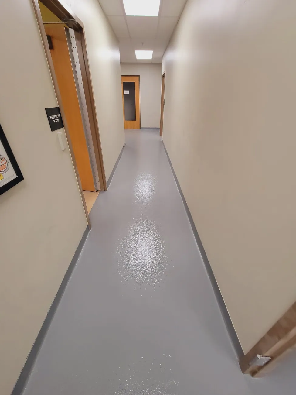 Long corridor with a gray epoxy floor reflecting the ceiling lights